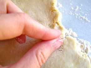 Pinching cracks in pie crust together with fingers.