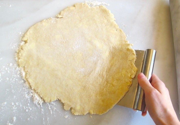 Scraping dough from floured marble surface.