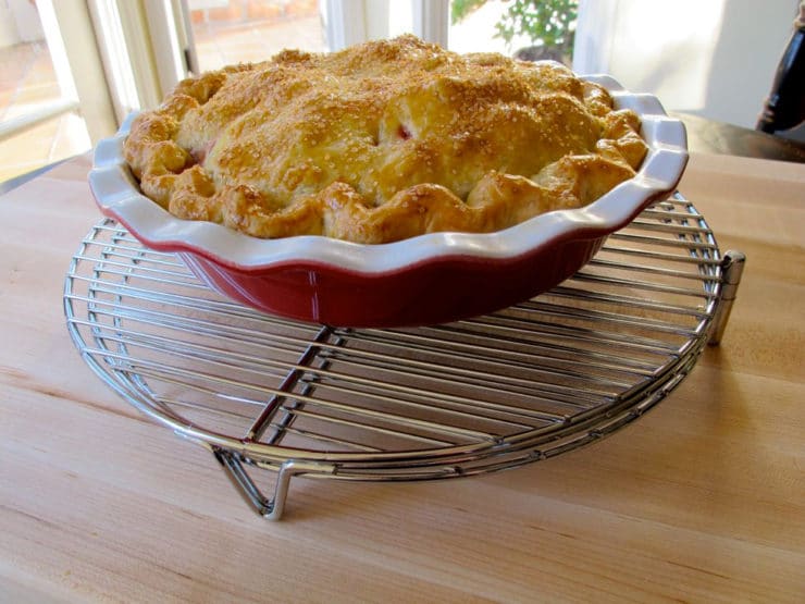Strawberry rhubarb pie cooling on a rack.
