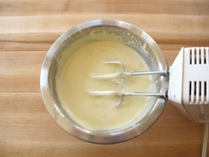Water and flour beat into egg yolks in a bowl.