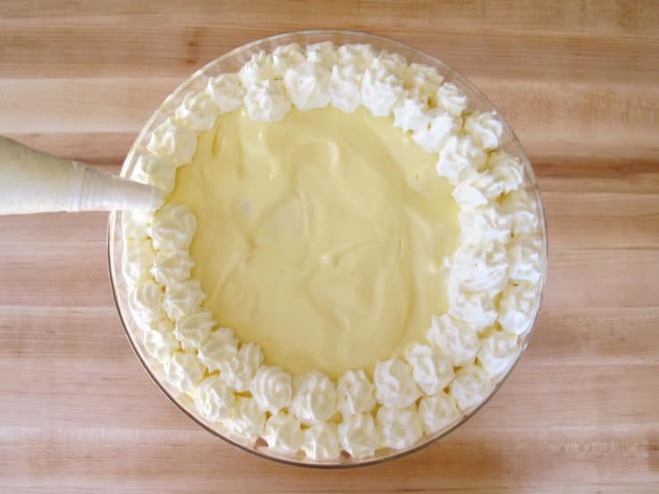Piping whipped cream stars on top of trifle.