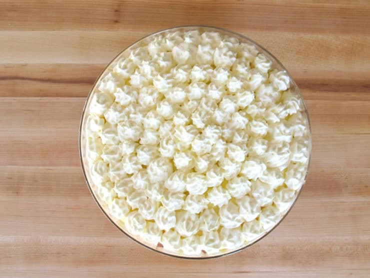 Piping whipped cream stars on top of trifle.
