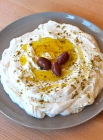 Strained yogurt labneh topped with olive oil and za'atar with three kalamata olives.