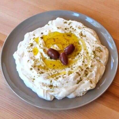 Strained yogurt labneh topped with olive oil and za'atar with three kalamata olives.