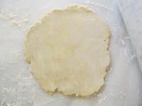 Pie crust dough rolled out on marble surface.