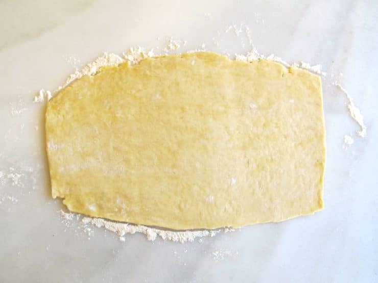 Rolled pie crust dough on marble surface.