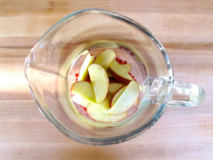 Apple slices added to a sangria pitcher.