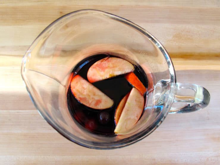 Bottle of red wine poured into sangria pitcher.