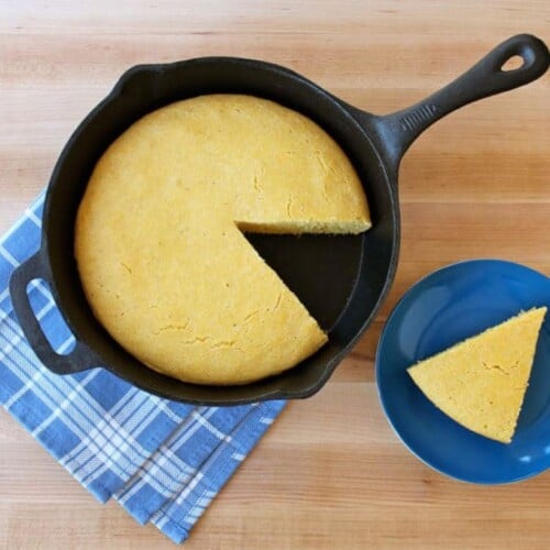 A Buttermilk Skillet Cornbread inside a pan and a single sliced Buttermilk Skillet Cornbread served on a blue plate