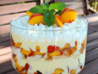A Tipsy Trifle with Peaches and Cream, a delectable dessert in a glass dish on a table