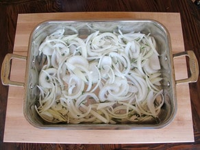 Sliced onions in a foil-lined baking pan.