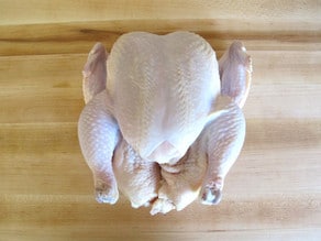 Whole chicken on cutting board.