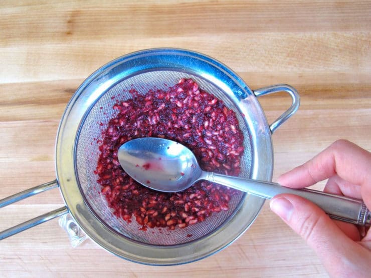 Use spoon to push all pomegranate juice through strainer.