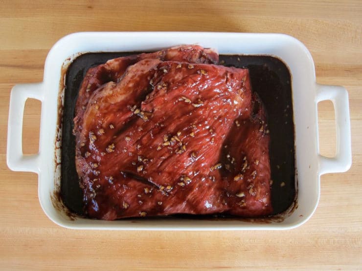 Pomegranate Molasses poured over brisket in a roasting pan.