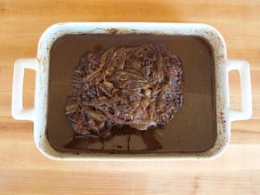 Cooked beef brisket in a roasting pan.