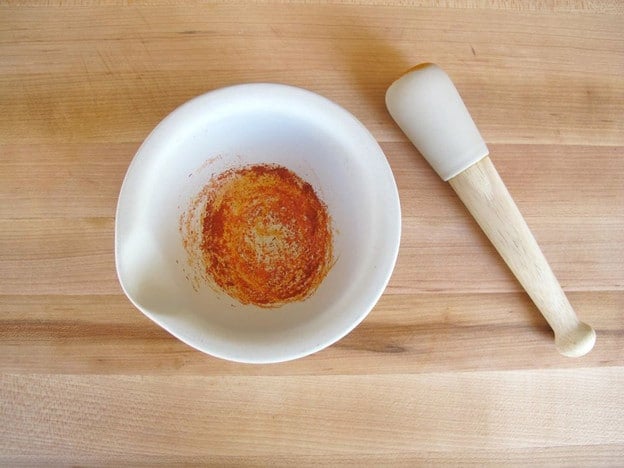 Ground saffron threads in a mortar and pestle.