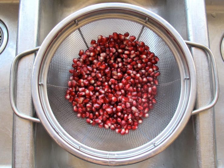 Pomegranate seeds draining in a strainer.