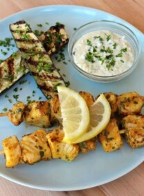 Grilled fish skewers with Mediterranean flavors on a plate with grilled eggplants and lemons