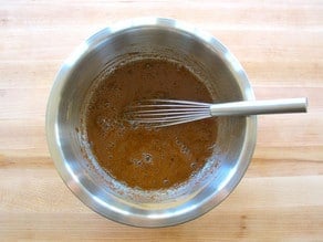 Whisking orange brown sugar marinade in a small bowl.