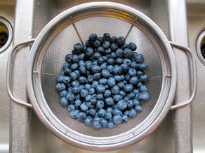 Rinsing fresh blueberries in a colander.