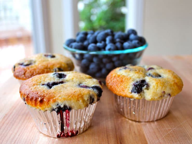 Three blueberry muffins with a side of fresh blueberries