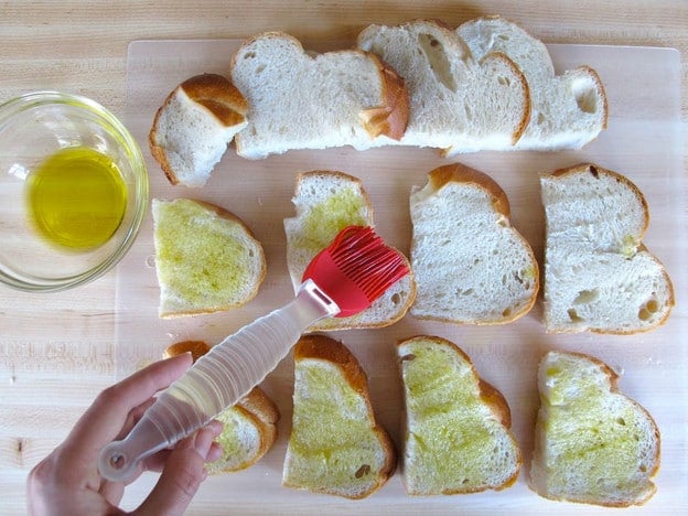 Brushing sliced challah with olive oil.