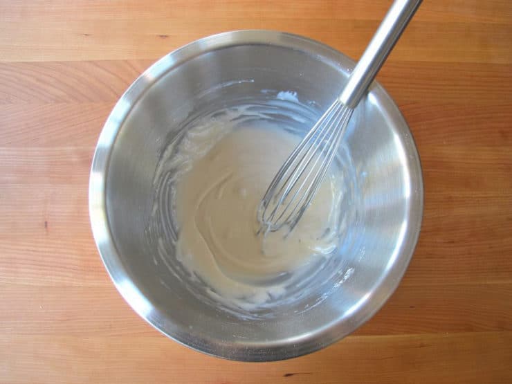 Whisking liquid into powdered sugar for frosting.