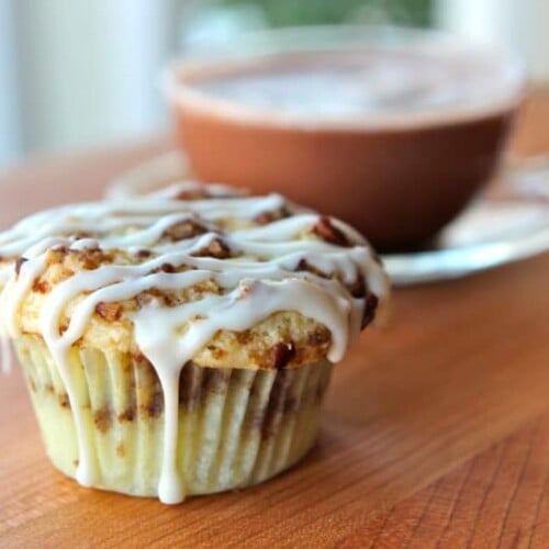 A Coffee Cake Cupcake with icing on top is placed on a wooden table.