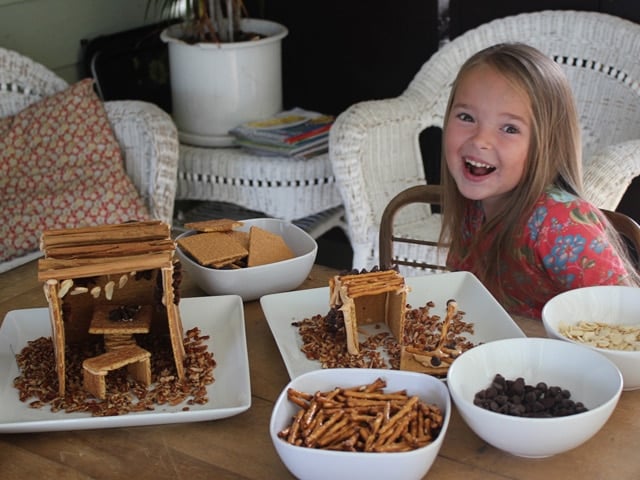 Smiling girl with food items to decorate her mini sukkah for Sukkot.