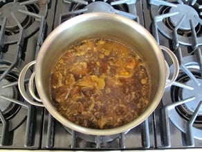 Water covering lamb and onion in a stockpot.