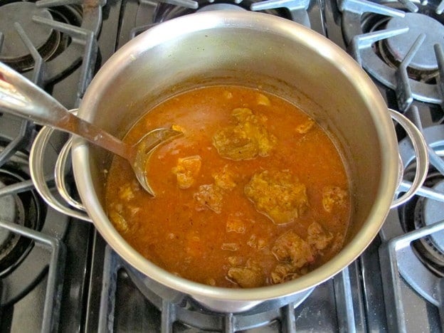 Stirring tomato paste into stockpot.