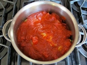 Layering cabbage rolls and tomato sauce in a pot.