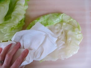 Drying cabbage leaves with a paper towel.