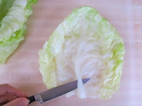 Removing tough stem from cabbage leaves.