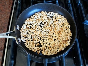 Pine nuts dry toasting in a skillet.