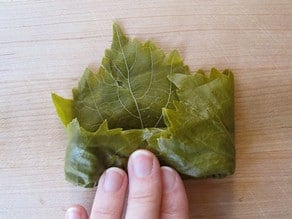 Fold grape leaf edges inward.