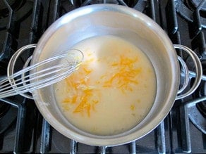 Whisking shredded cheese into a roux.