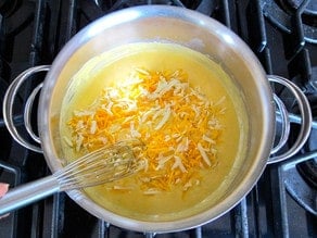 Whisking shredded cheese into a roux.
