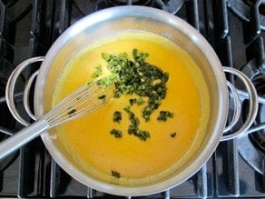Stirring diced jalapenos into cheese sauce.