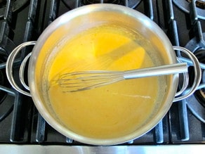 Smoothly melted cheese sauce in a saucepan.
