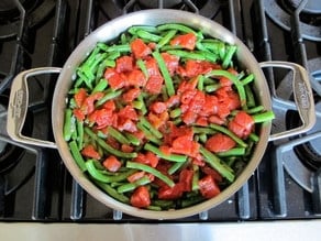 Tomatoes added to green beans in skillet.