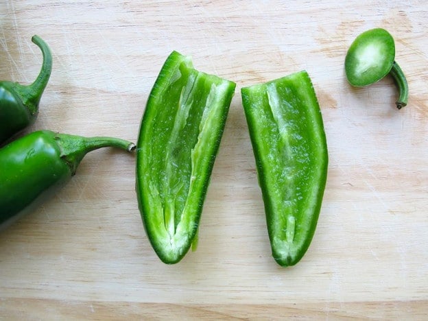 Seeded jalapeno halves on cutting board.
