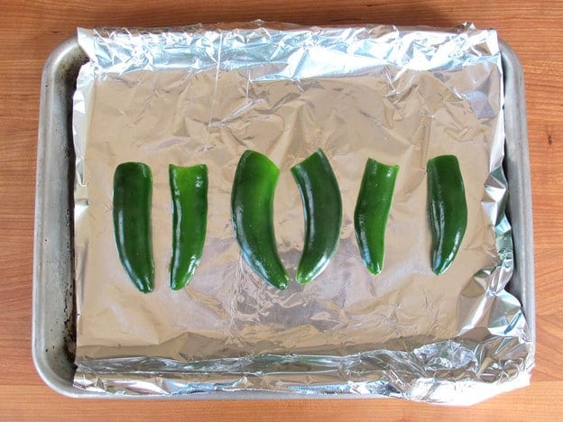 Fresh seeded jalapeno halves on baking sheet.