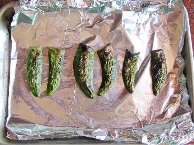Oven roasted jalapeno halves on baking sheet.