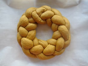 Braided challah circle on a parchment lined sheet.