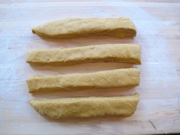 Slice the dough rectangle into four long equal-sized strips.