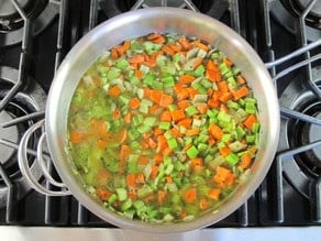 Chicken stock added to carrots and celery in a skillet.