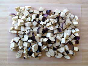 Cubed eggplant piled on a cutting board.