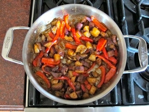 Sauce poured over eggplant and peppers in skillet.