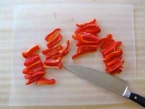 Thinly sliced red bell pepper on a cutting board.